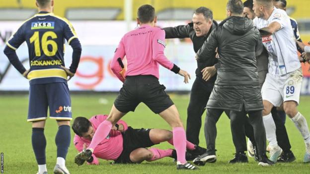 Referee Halil Umut Meler falls to the ground after Faruk Koca, president of MKE Ankaragucu throws a punch