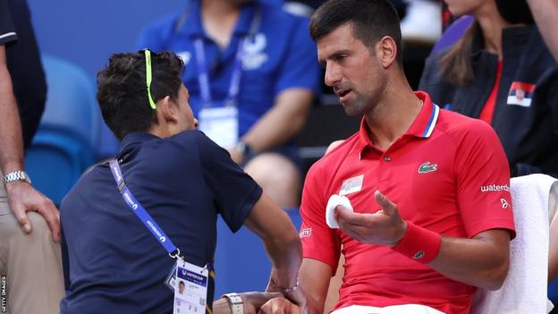 Novak Djokovic speak to the trainer during his defeat to Alex de Minaur at the United Cup