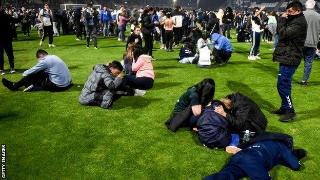 Gimnasia y Esgrima La Plata fans react in the stadium after being hit by tear gas