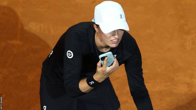 Iga Świątek reacts to her mobile phone during a match at the Italian Open