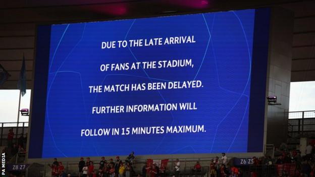 A message on the screen inside the Stade de France explains the match was postponed due to "late arrival of fans"