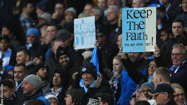 Fans hold up supportive banners at Etihad Stadium