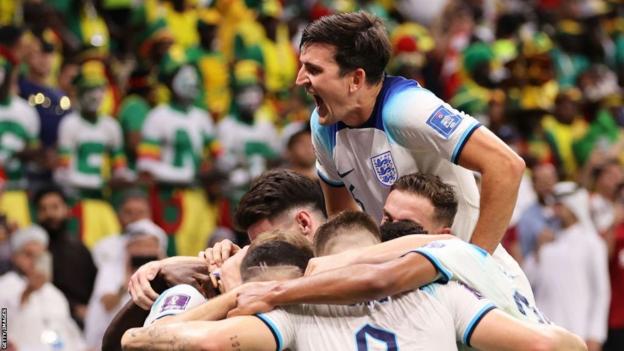Harry Maguire jumps over his team as they celebrate a goal against Senegal
