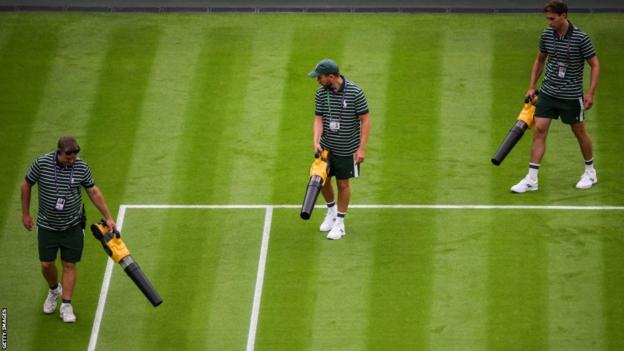 Ground staff try to dry the court with dryers