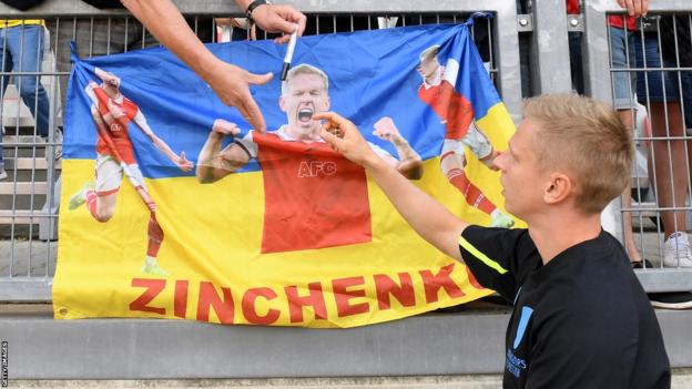 Oleksandr Zinchenko signs a Ukrainian flag with his image on during Arsenal's pre-season tour of the United States