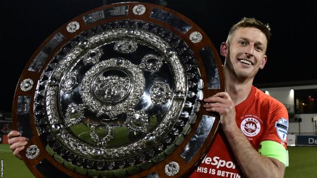 Jeff Hughes celebrates with the County Antrim Shield after Larne beat Glentoran in the 2020 final