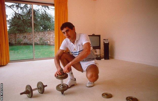 Ayrton Senna in a sparse living room with some dumbells
