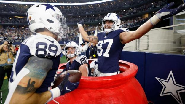 The Dallas Cowboys celebrate in the Salvation Army kettle