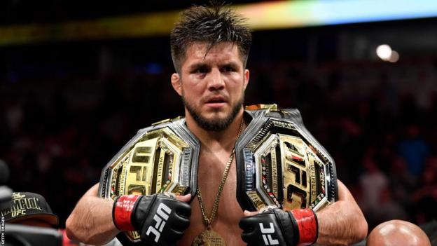 Henry Cejudo with the UFC bantamweight and flyweight belts