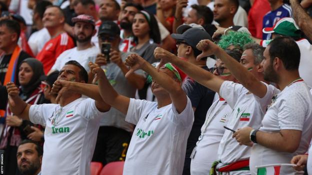 Some supporters of Iran react to their national anthem during the game against Wales
