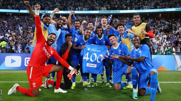 Al-Hilal's players celebrate after defeating Al-Ittihad holding a match shirt to celebrate the 400th appearance for Yasser Al-Shahrani