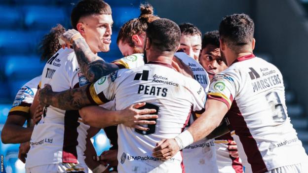 Huddersfield's Owen Trout is mobbed by teammates such as Esan Marsters and Nathan Peats after one of his tries