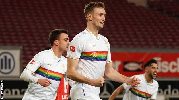 Stuttgart players celebrate while wearing a rainbow-striped kit in a Bundesliga match against Mainz