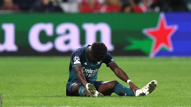Arsenal's Bukayo Saka is down injured during the match against Lens