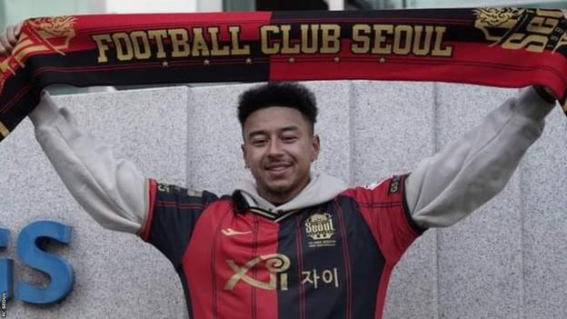 Jesse Lingard holds an FC Seoul scarf aloft