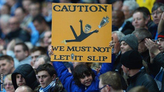 Fan holds up a banner with a picture of Steven Gerrard and the words: 'Caution: We must not let it slip'