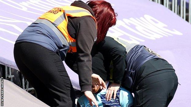 Swansea stewards remove a fan wearing a Wycombe Wanderers shirt from Liberty Stadium