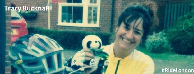 Tracy Bucknall holding a cuddly toy panda in her garden, just in view here cycle helmet rests on her handle bars of her bike