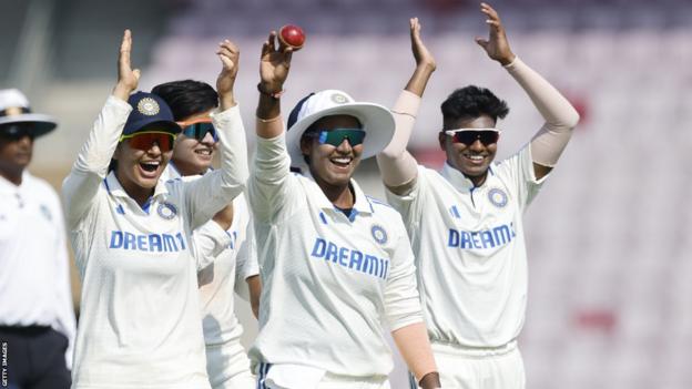 Indian spinner Deepti Sharma (middle) lifts the ball after taking five wickets against England and is applauded by her teammates