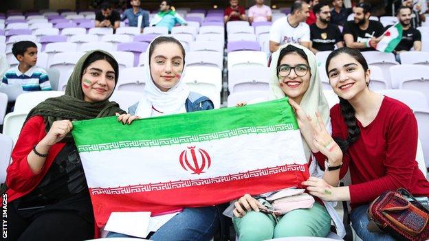 Female Iran fans hold aloft a flag