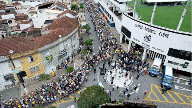 ผู้ร่วมไว้อาลัยยืนเข้าแถวนอกสนามกีฬา Vila Belmiro ขณะที่พวกเขารอการแสดงความเคารพต่อ Pele