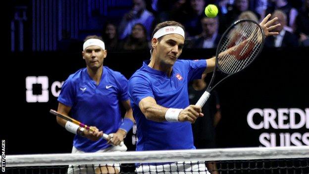 Roger Federer hits a volley as Rafael Nadal watches on in their Laver Cup match