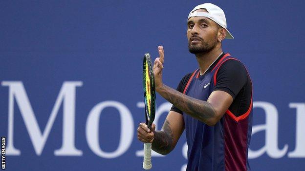 Nick Kyrgios claps his hand on his racquet