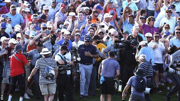 Phil Mickelson (centre) is surrounded by the crowd on the fairway as he heads towards the green on the eighteenth hole