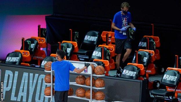 Workers remove items from the Milwaukee Bucks' bench area after they boycott an NBA play-off game