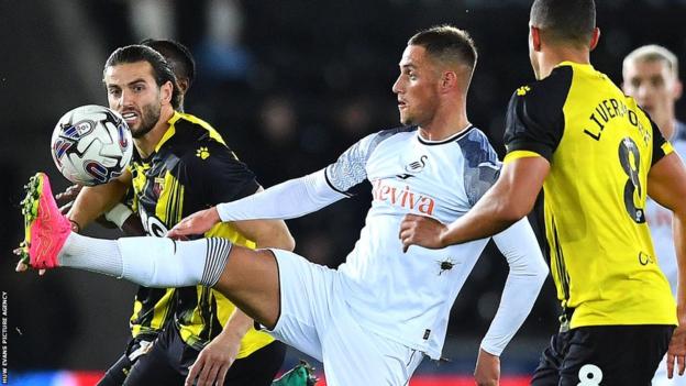 Jerry Yates of Swansea City (centre) is tackled by Wesley Hoedt (left) of Watford
