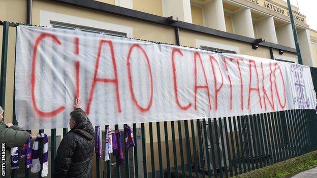 A banner reading "Ciao Captain" is tied to the gates of Fiorentina's stadium