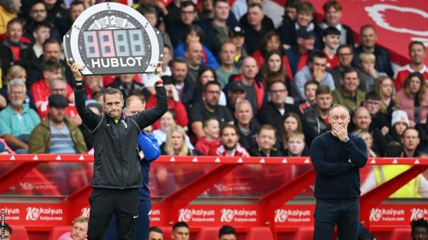 Fourth Official Craig Pawson holds up the extra time board which reads "13" minutes as Steve Cooper, manager of Nottingham Forest, reacts