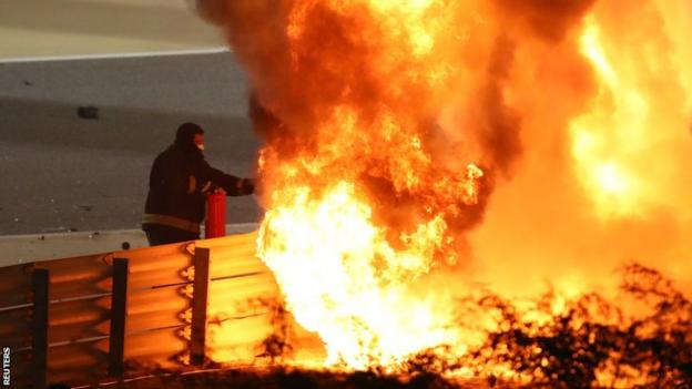 Marshals try to put out the flames on Grosjean's car