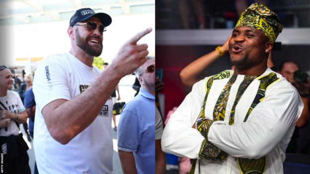 Tyson Fury pointing and smiling beside a representation   of Francis Ngannou smiling