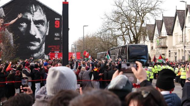 Fans take pictures as the Manchester United team bus arrives at Anfield