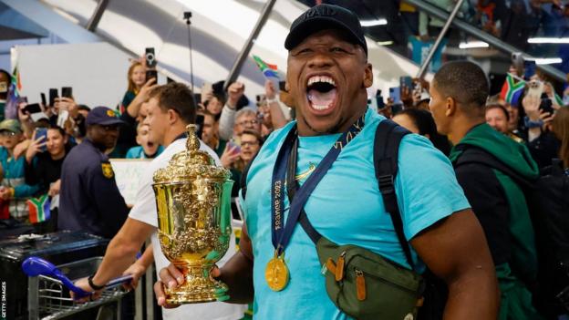 Bongi Mbonambi with the Rugby World Cup trophy after the South African team's arrival at the OR Tambo International airport on 31 October