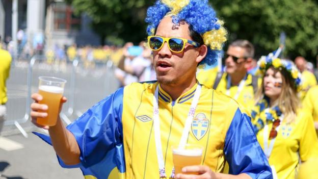 Swedish football fan holding two beers