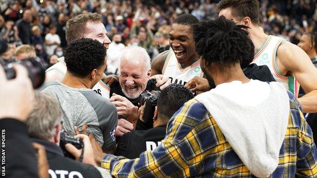 San Antonio Spurs head coach Gregg Popovich is congratulated by players after becoming the winningest coach in NBA history
