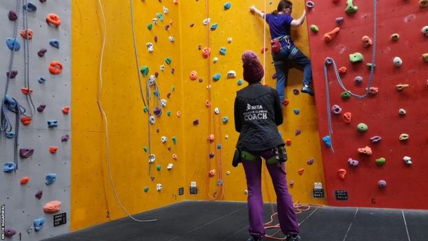 Anita Aggarwal stood watching and coaching a climber attempting to go up a wall