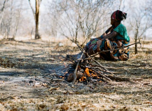 A Hadza woman sits by a campfire