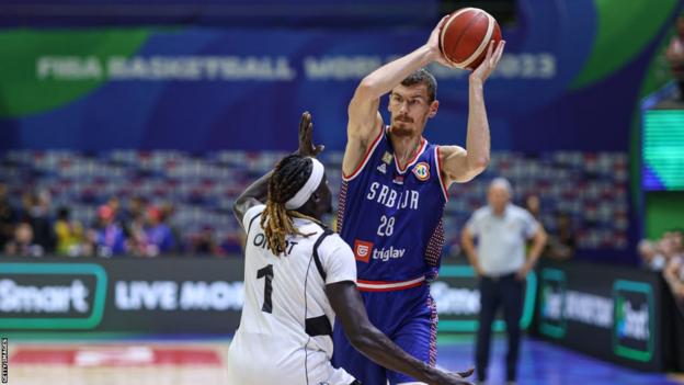 Borisa Simanic holds the basketball in front of Nuni Omot