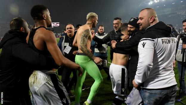 Akpom (second left) and PAOK keeper Alexandros Paschalakis (centre) are mobbed by fans after the win over Olympiakos in February