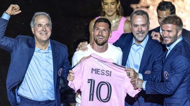 Lionel Messi brandit un maillot de l'Inter Miami aux côtés du propriétaire du club Jorge Mas (L), Jose Mas et du copropriétaire David Beckham