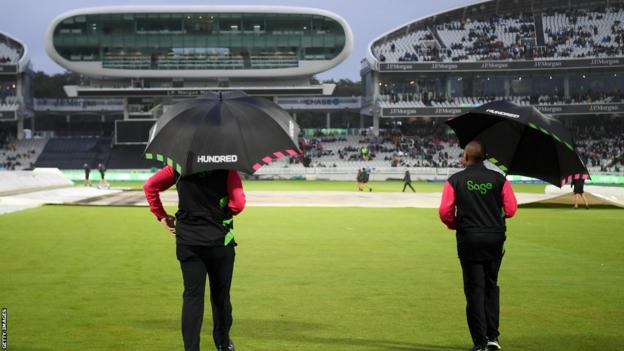 The umpires going out to inspect the pitch in the rain at Lord's