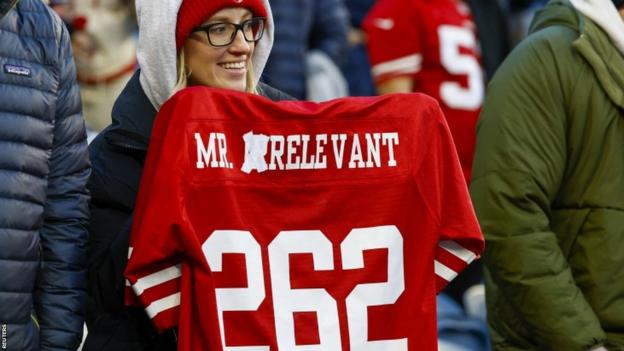 A San Francisco 49ers fan holding a jersey with Mr Irrelevant changed to Mr Relevant for Brock Purdy