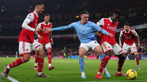 Manchester City's Phil Foden challenges Arsenal forward Bukayo Saka for the ball at Emirates Stadium