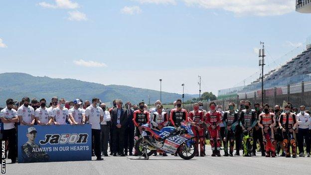 Riders and support staff observe a minute of silence in tribute to Dupasquier