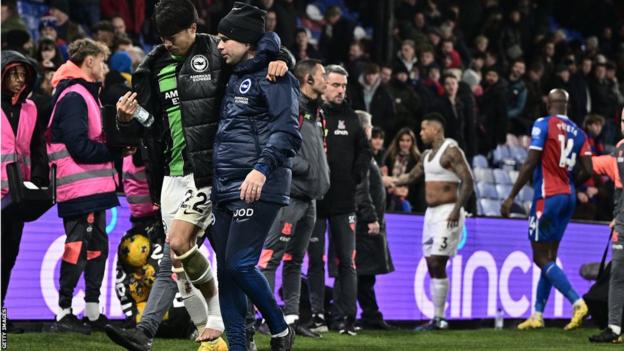 Kaoru Mitoma is helped off the pitch after he was injured against Crystal Palace