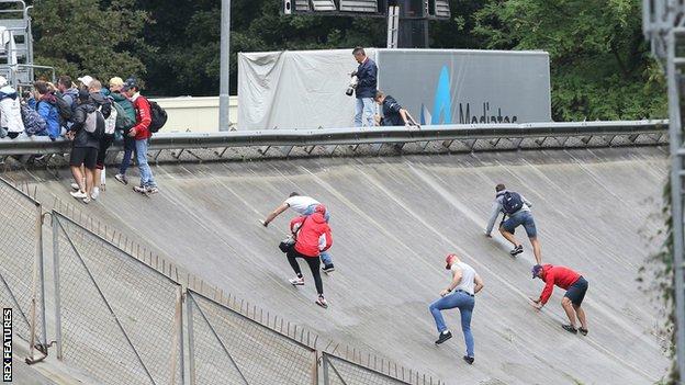Spectators scramble up the steep banking of a former track to get the best view on the first day of practice at Monza