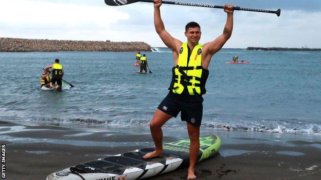 Ben Youngs stands on a paddleboard